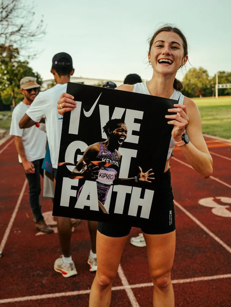 Runner holding the I’VE GOT FAITH Breaking4 poster at a track
