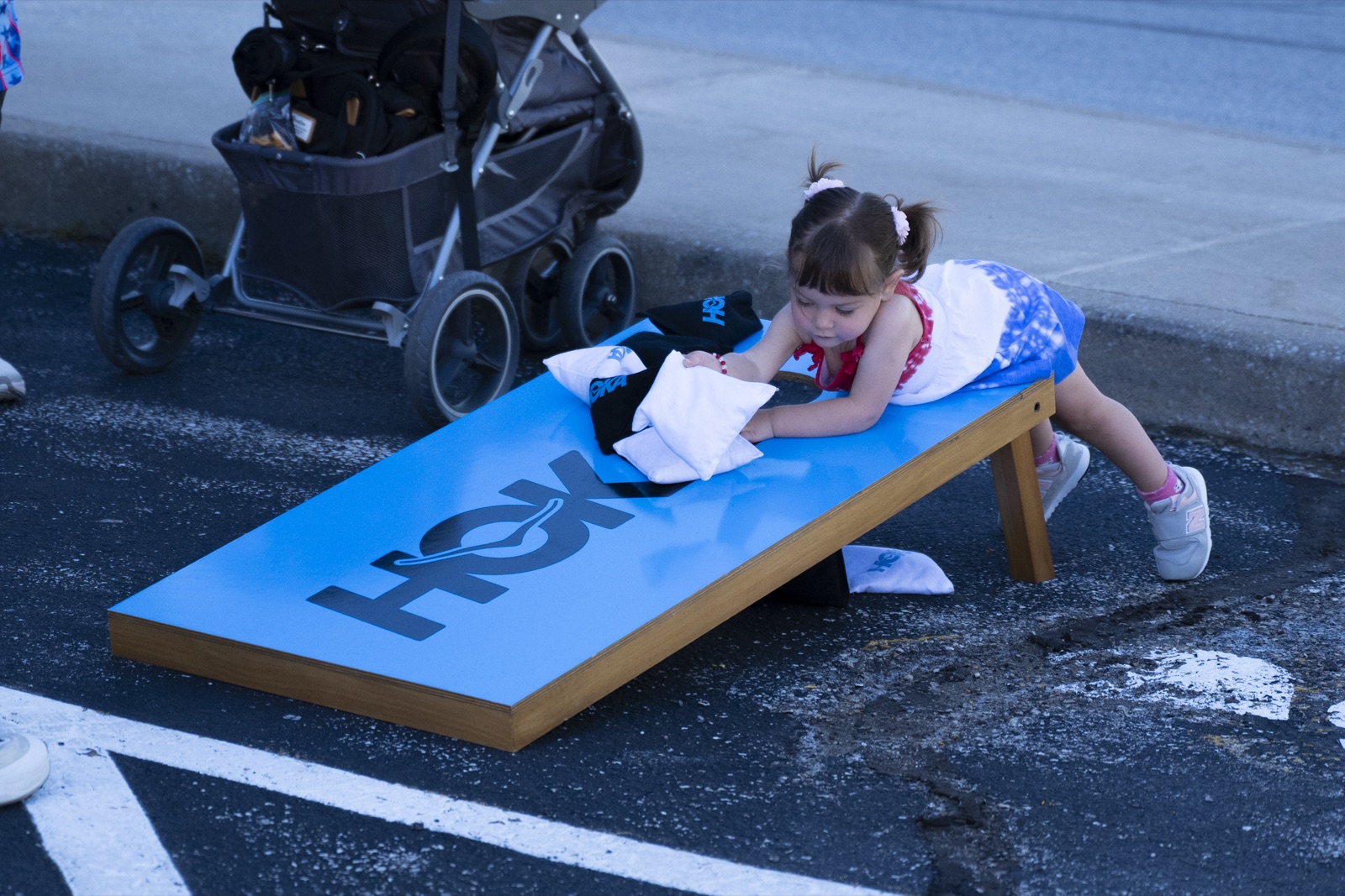 A young fan playing on a HOKA-branded cornhole board at Festival of Miles