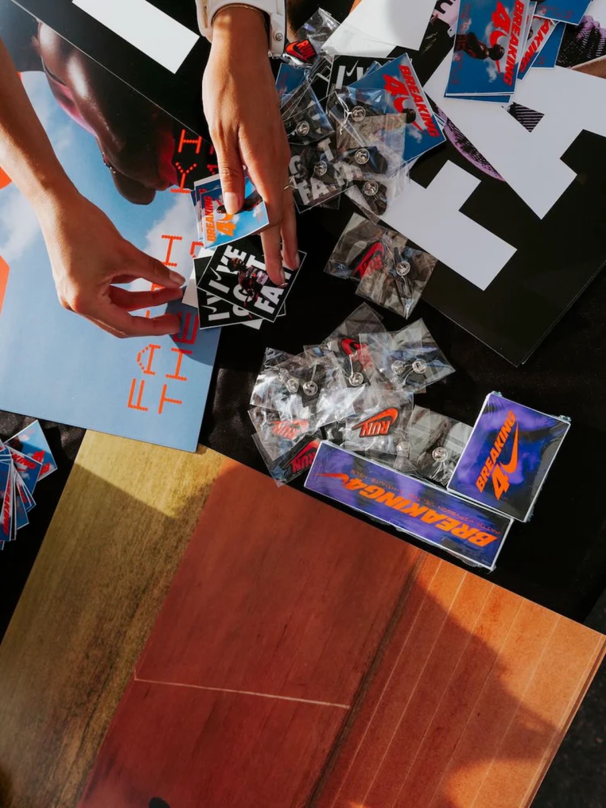 Breaking4 die-cut sticker packs, bagged enamel pins, and posters laid out on a merch table